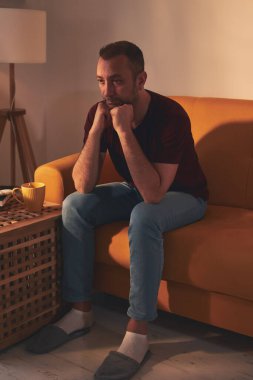 Uyuşukluk ve ilgisizlikle sıkılmış adam evde tek başına oturuyor..