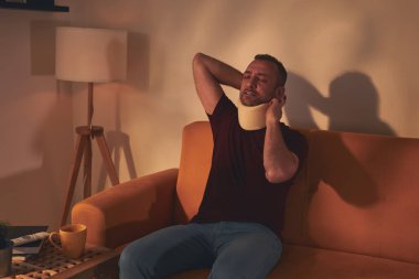 Servikal yakalı ve boynu ağrıyan bir adam..