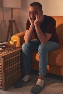 Uyuşukluk ve ilgisizlikle sıkılmış adam evde tek başına oturuyor..