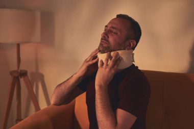 Servikal yakalı ve boynu ağrıyan bir adam..