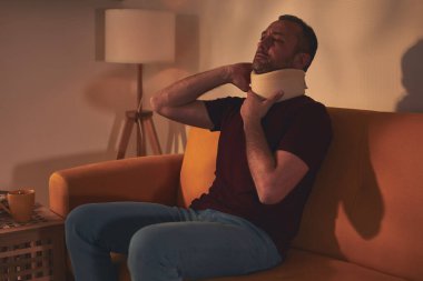 Servikal yakalı ve boynu ağrıyan bir adam..