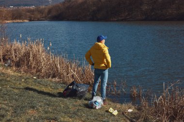 Gönüllü ve çevreci eylemci çöplerle dolu kirli göl kıyılarını temizliyor..