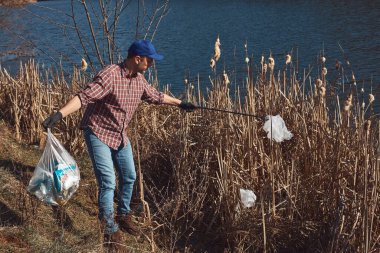 Gönüllü ve çevreci eylemci çöplerle dolu kirli göl kıyılarını temizliyor..