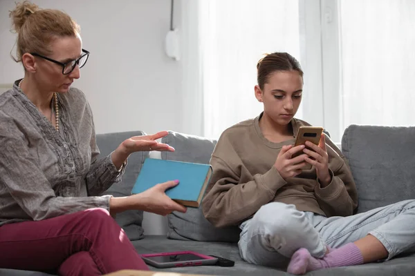 スマートフォンでビデオゲームをプレイしながら お母さんは自宅で怠惰なティーンエイジャーの女の子と問題を抱えています — ストック写真