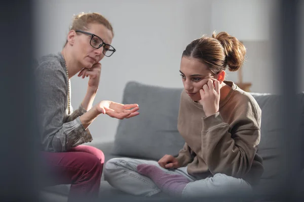 Mother talking with difficult teenager daughter at home.