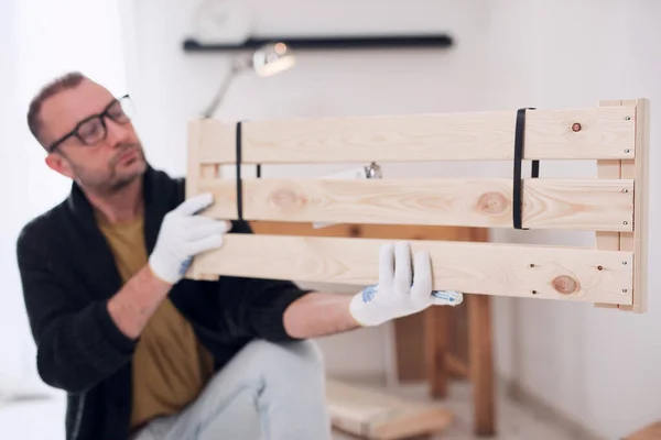 stock image Man assembling new wooden shelf and furniture in the apartment.