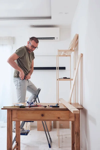 Man Monteert Nieuwe Houten Plank Meubels Het Appartement — Stockfoto