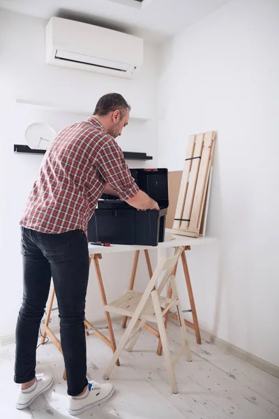 Yeni ahşap bir raf ve mobilya monte eden bir adam..