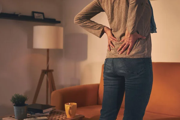 Woman with hip and back pain at home.