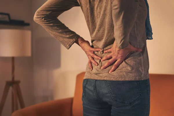 Woman with hip and back pain at home.