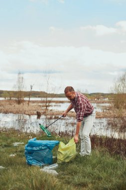 Gönüllü ve çevreci eylemci çöplerle dolu kirli göl kıyılarını temizliyor..