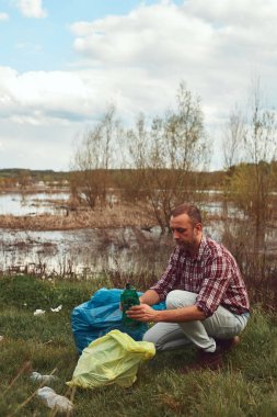 Gönüllü ve çevreci eylemci çöplerle dolu kirli göl kıyılarını temizliyor..