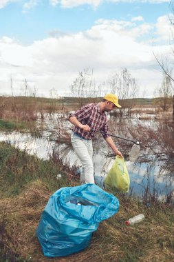 Gönüllü ve çevreci eylemci çöplerle dolu kirli göl kıyılarını temizliyor..