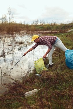 Gönüllü ve çevreci eylemci çöplerle dolu kirli göl kıyılarını temizliyor..