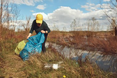 Gönüllü ve çevreci eylemci çöplerle dolu kirli göl kıyılarını temizliyor..