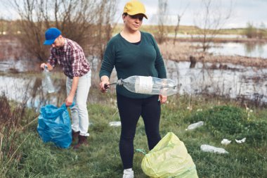 Gönüllüler ve çevreciler çöplerle dolu kirli göl kıyılarını temizliyorlar..
