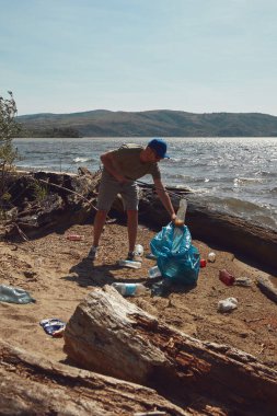 Gönüllü ve çevreci eylemci çöplerle dolu kirli nehir kıyılarını temizliyor..