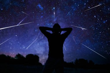 Samanyolu yıldızlı gökyüzüne sahip bir adamın silueti.