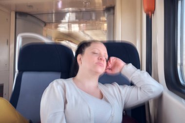 Bir kadın seyahat ederken tren koltuğunda uyuyor..