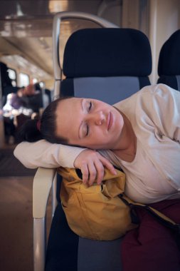Bir kadın seyahat ederken tren koltuğunda uyuyor..