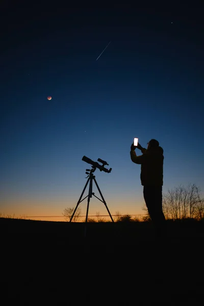 천문학자들 은행성으로 하늘을 바라보면서 현재의 스마트폰을 사용하는 망원경으로 떨어지는 월식을 — 스톡 사진