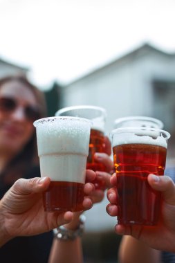 İnsanlar ellerinde bira bardakları tutarak yaz tatilinin tadını çıkarıyorlar..