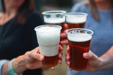 İnsanlar ellerinde bira bardakları tutarak yaz tatilinin tadını çıkarıyorlar..