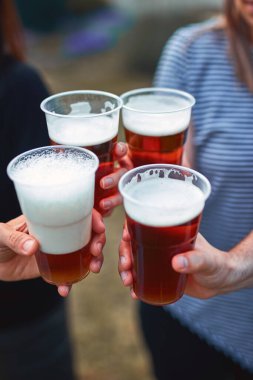 İnsanlar ellerinde bira bardakları tutarak yaz tatilinin tadını çıkarıyorlar..