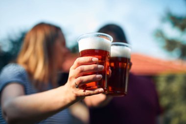 İnsanlar ellerinde bira bardakları tutarak yaz tatilinin tadını çıkarıyorlar..