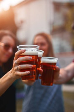 İnsanlar ellerinde bira bardakları tutarak yaz tatilinin tadını çıkarıyorlar..