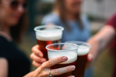 İnsanlar ellerinde bira bardakları tutarak yaz tatilinin tadını çıkarıyorlar..