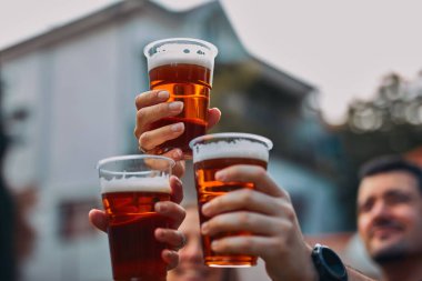 İnsanlar ellerinde bira bardakları tutarak yaz tatilinin tadını çıkarıyorlar..