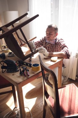 Mobilya onarımı ve restorasyonu için küçük bir ev atölyesinde çalışan bir adam.