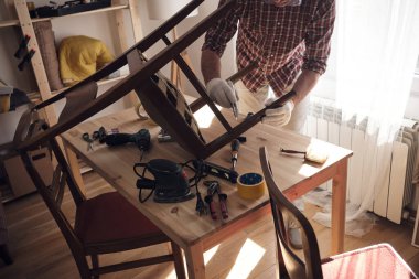 Mobilya onarımı ve restorasyonu için küçük bir ev atölyesinde çalışan bir adam.