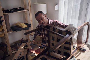 Mobilya onarımı ve restorasyonu için küçük bir ev atölyesinde çalışan bir adam.