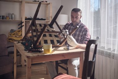 Mobilya onarımı ve restorasyonu için küçük bir ev atölyesinde çalışan bir adam.