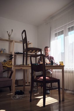 Mobilya onarımı ve restorasyonu için küçük bir ev atölyesinde çalışan bir adam.