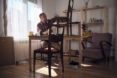 Mobilya onarımı ve restorasyonu için küçük bir ev atölyesinde çalışan bir adam.