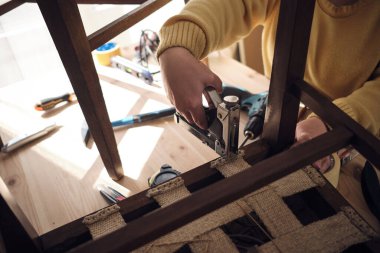 Mobilya onarımı ve restorasyonu için küçük bir ev atölyesinde çalışan bir kadın.