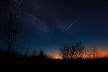 Kayan yıldız, Samanyolu ve manzara siluetleri.