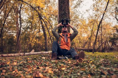 Dürbün ve kamera kullanan adam doğada kuşları ve hayvanları izliyor..