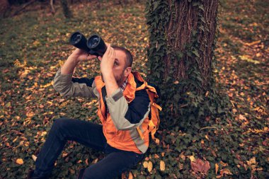 Dürbün ve kamera kullanan adam doğada kuşları ve hayvanları izliyor..