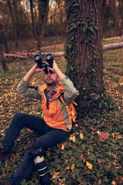 Dürbün ve kamera kullanan adam doğada kuşları ve hayvanları izliyor..