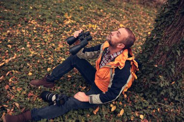 Dürbün ve kamera kullanan adam doğada kuşları ve hayvanları izliyor..