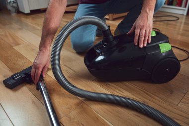 Adam elektrikli süpürgeyle daireyi temizliyor..