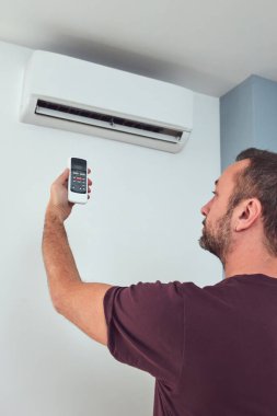 Modern bir klima kumandası tutan adam..