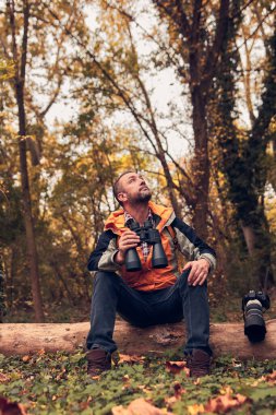 Dürbün ve kamera kullanan adam doğada kuşları ve hayvanları izliyor..