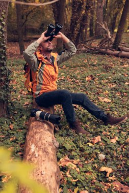 Dürbün ve kamera kullanan adam doğada kuşları ve hayvanları izliyor..