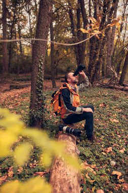 Dürbün ve kamera kullanan adam doğada kuşları ve hayvanları izliyor..