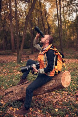 Man using binoculars and camera for bird and animal watching in nature. clipart